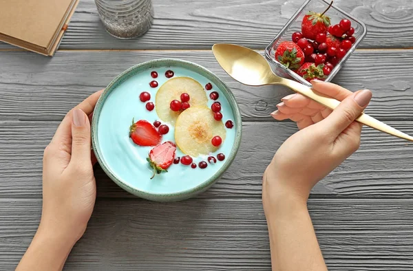 Femme mangeant un smoothie bleu spiruline à table. Concept d'alimentation végétalienne saine — Photo