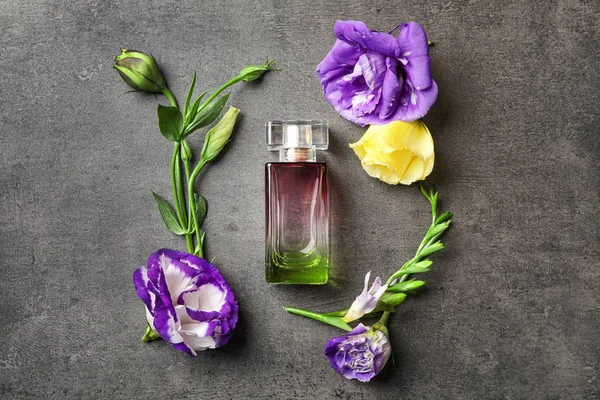 Butelek perfum z kwiatami na szarym tle — Zdjęcie stockowe