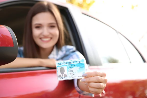 Jovem mulher feliz segurando carta de condução no carro — Fotografia de Stock