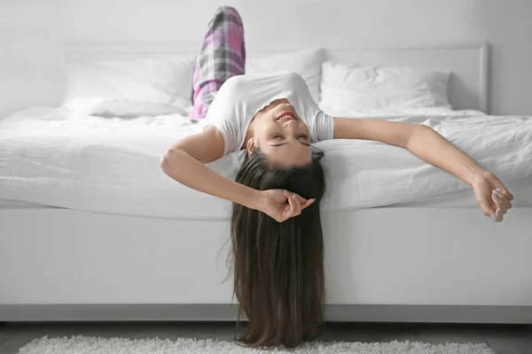 Jonge vrouw ondersteboven liggend in bed thuis — Stockfoto