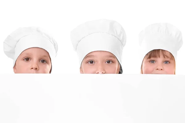 Crianças bonitos em chapéus de chef segurando cartaz em branco no fundo branco — Fotografia de Stock