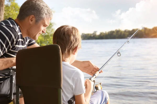 Father with son fishing from riverside — Stock Photo, Image