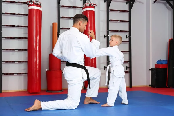 Instructor de karate masculino entrenando a un niño pequeño en dojo — Foto de Stock