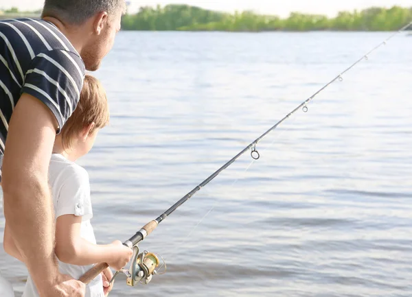 Padre con hijo pesca desde la orilla del río — Foto de Stock