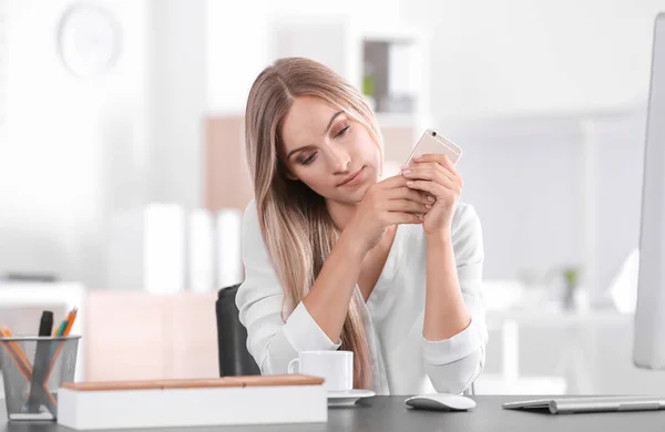 Young woman using smartphone in office — Stock Photo, Image