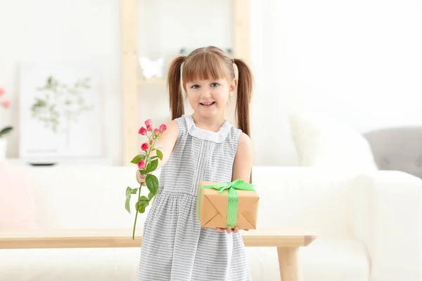 Liten flicka innehav presentbox och blomma för mors dag hemma — Stockfoto