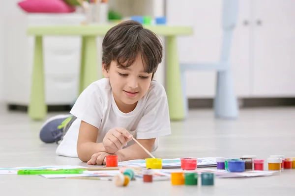 Kleiner Junge malt, während er zu Hause auf dem Boden liegt — Stockfoto