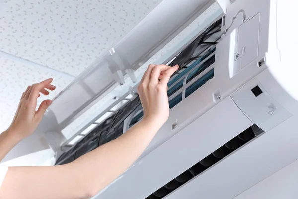 Young woman cleaning air conditioner, indoors — Stock Photo, Image