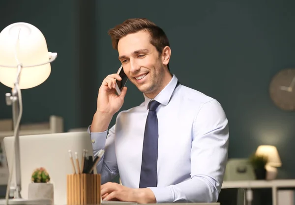 Young man with mobile phone working in office at night — Stock Photo, Image