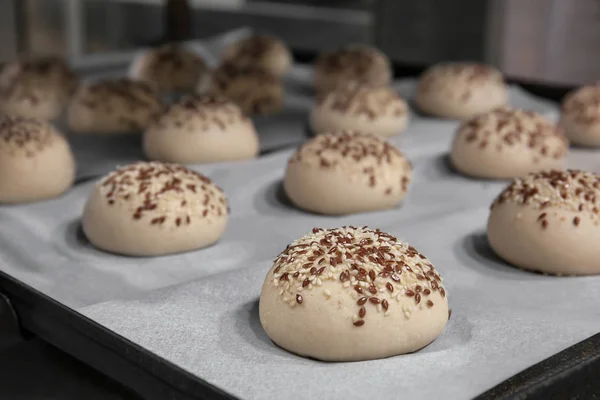 Buns with sesame on baking tray — Stock Photo, Image