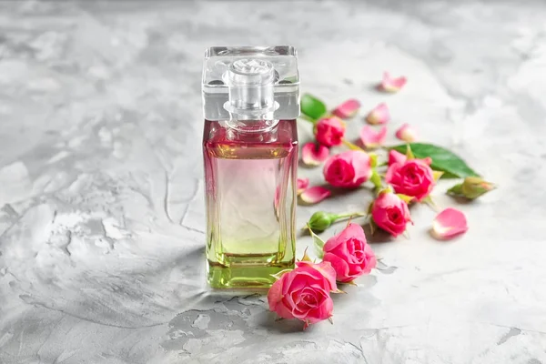 Butelek perfum z kwiatami na jasnym tle — Zdjęcie stockowe