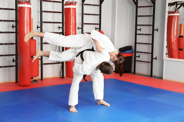 Young man and woman practicing martial arts in dojo — Stock Photo, Image