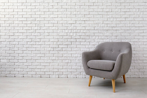 Comfortable armchair near brick wall