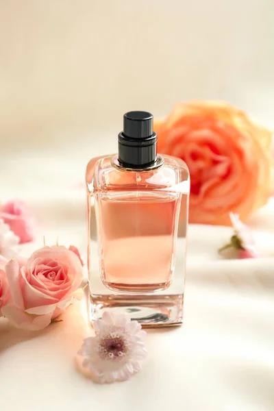 Lahvička parfému s květinami na lehké látce — Stock fotografie