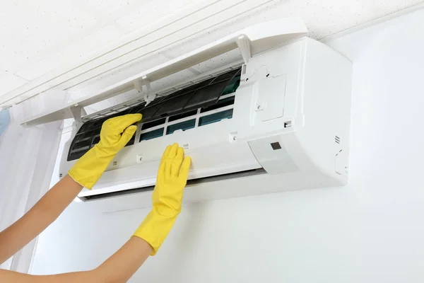 Jonge vrouw controleren airconditioner thuis — Stockfoto