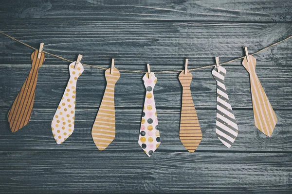 Happy Den otců koncept. Kravaty vyrobené z papíru, visí na laně dřevěné pozadí — Stock fotografie
