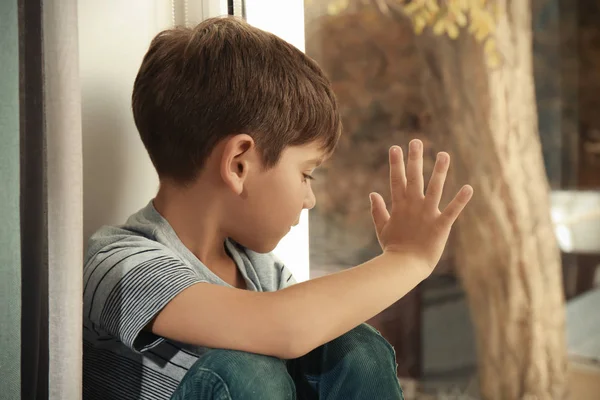 Un niño triste cerca de la ventana. Abuso del concepto de niños —  Fotos de Stock