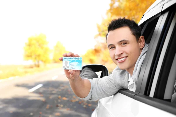 Young man holding driving license in car — Stock Photo, Image