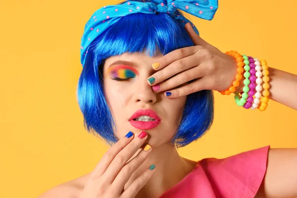 Jovem com maquiagem arco-íris e cabelo azul no fundo amarelo — Fotografia de Stock
