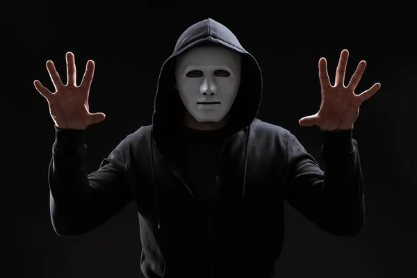 Hacker em máscara trabalhando com tela virtual em fundo escuro — Fotografia de Stock