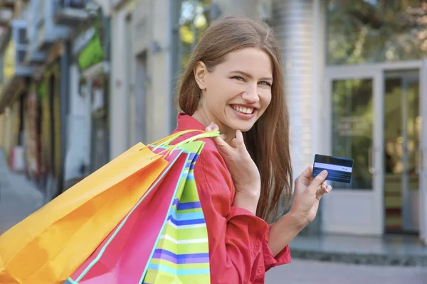 Jovem com sacos de compras e cartão de crédito, ao ar livre — Fotografia de Stock