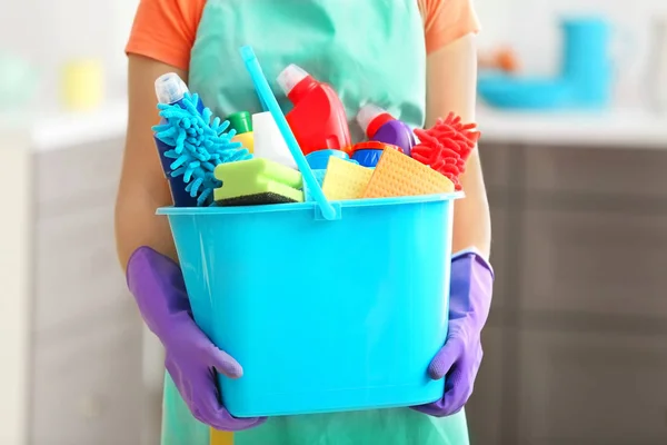 Mulher segurando balde com produtos de limpeza e ferramentas dentro de casa — Fotografia de Stock