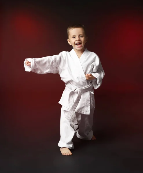 Kleiner Junge übt Karate auf dunklem Hintergrund — Stockfoto