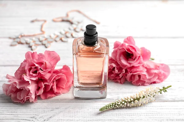 Láhev parfém a čerstvé květiny na dřevěné pozadí — Stock fotografie