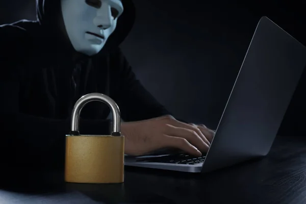 Лок на столе и хакер с помощью ноутбука на темном фоне — стоковое фото