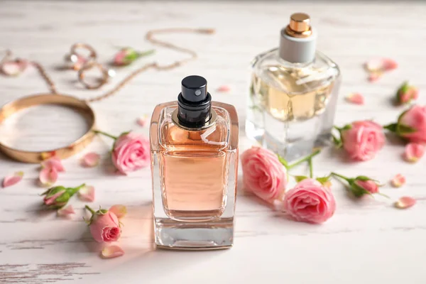 Lahvičky s parfémy s květinami na světlé pozadí — Stock fotografie