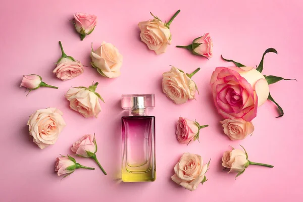 Botella de perfume con flores sobre fondo de color — Foto de Stock