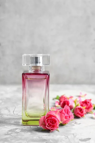 Bottle of perfume with flowers on light background — Stock Photo, Image