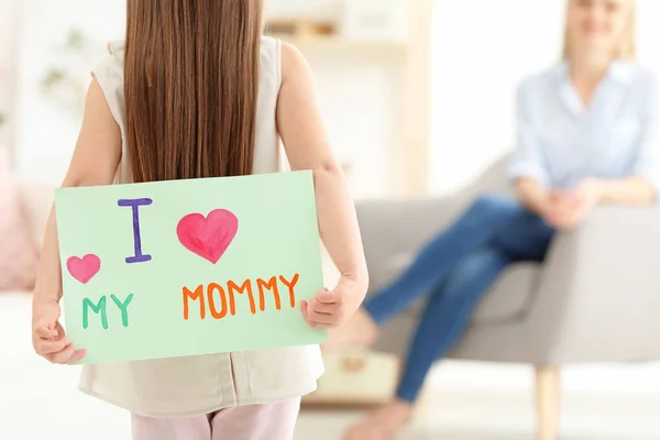 Liten flicka gömmer gratulationskort för mors dag bakom hennes rygg hemma — Stockfoto
