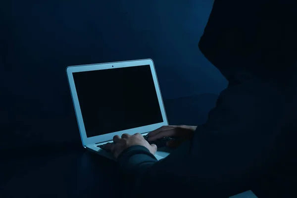 Haker przy użyciu laptopa na ciemnym tle — Zdjęcie stockowe