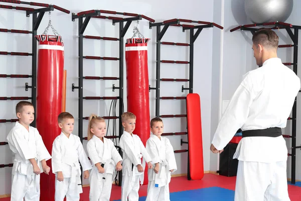 Instructor de karate masculino entrenando a niños pequeños en dojo — Foto de Stock