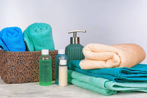 Clean towels and cosmetics on table against light background