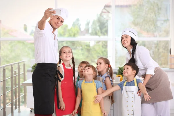 Dois chefs e crianças bonitos tomando selfie depois de aulas de culinária — Fotografia de Stock