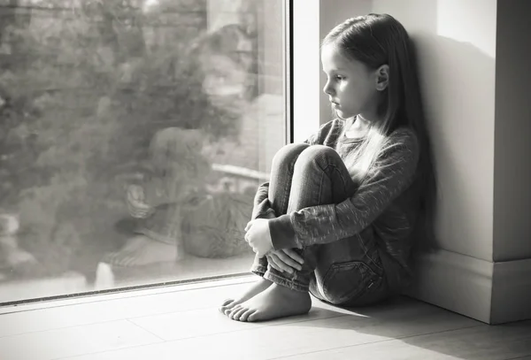 Niña triste cerca de la ventana. Abuso del concepto de niños — Foto de Stock