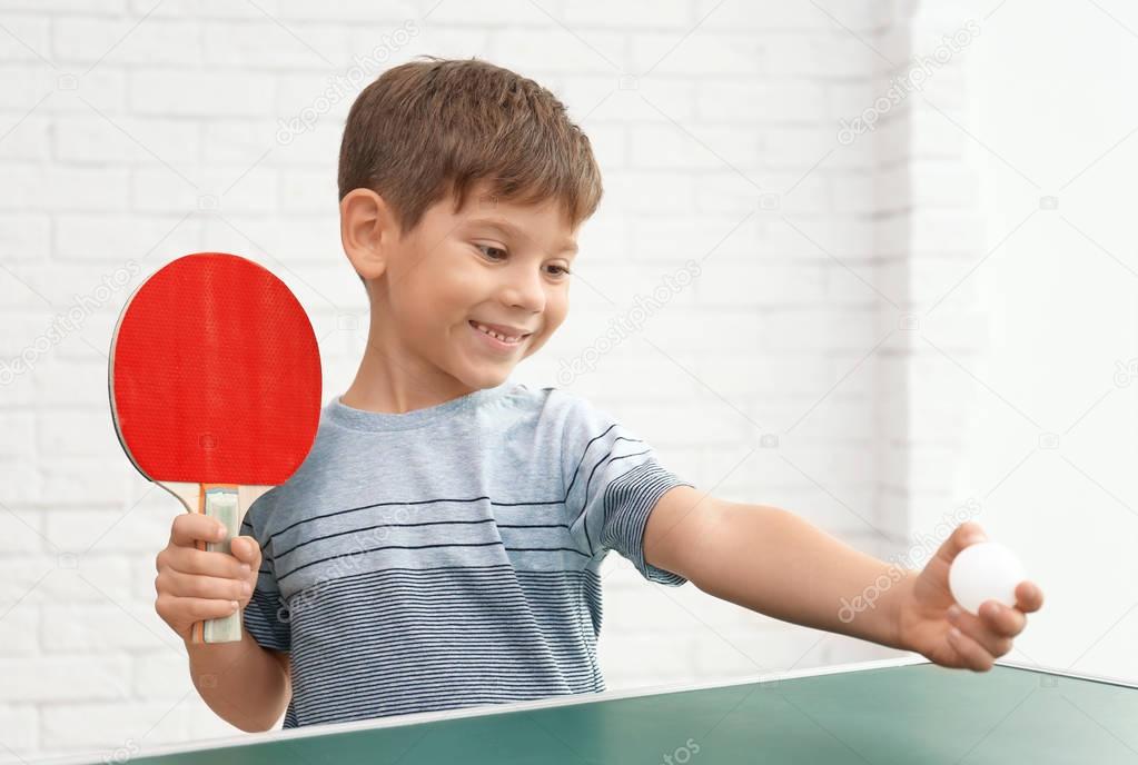 Cute little boy playing table tennis indoors