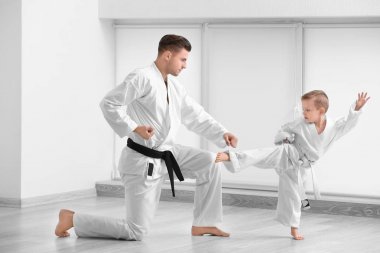 Little boy with instructor practicing karate in dojo clipart