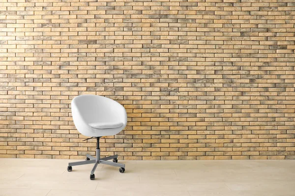 Удобное кресло возле кирпичной стены — стоковое фото