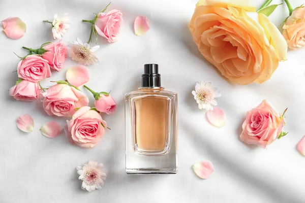 Botella de perfume con flores sobre tela ligera — Foto de Stock