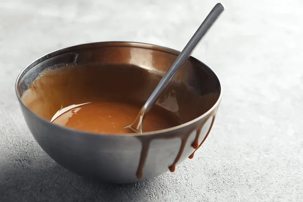 Bowl with sweet caramel sauce on table — Stock Photo, Image