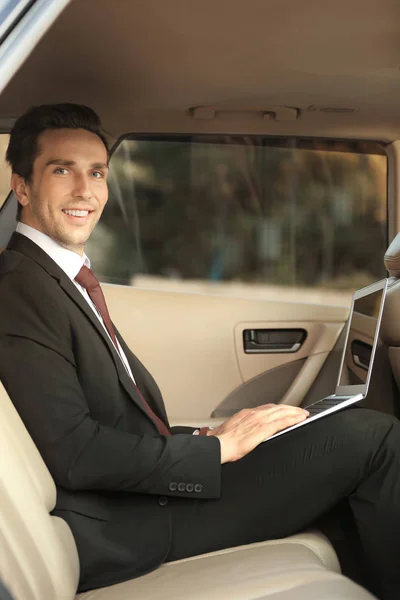 Man in formal wear with laptop in car — Stock Photo, Image