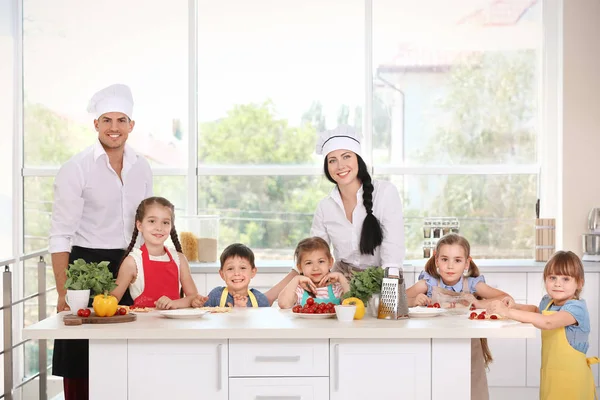 Dois chefs e grupo de crianças durante as aulas de culinária — Fotografia de Stock