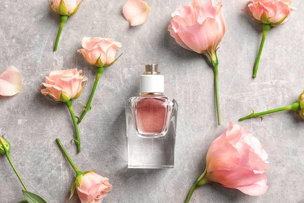Butelek perfum i kwiatów na szarym tle — Zdjęcie stockowe