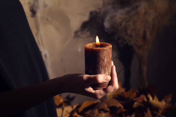 Mystic person holding burning candle. Halloween concept