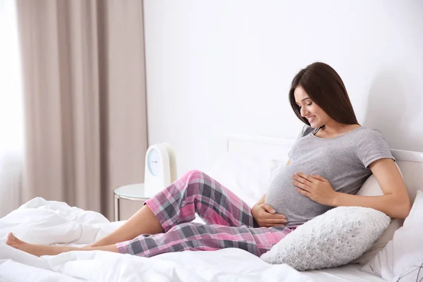 若いです妊娠中の女性座っていますベッドに家 — ストック写真