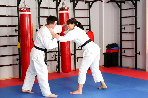 Young man and woman practicing karate in dojo — Stock Photo, Image