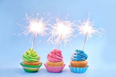 Işık arka plan üzerinde havai fişekleri ile lezzetli cupcakes